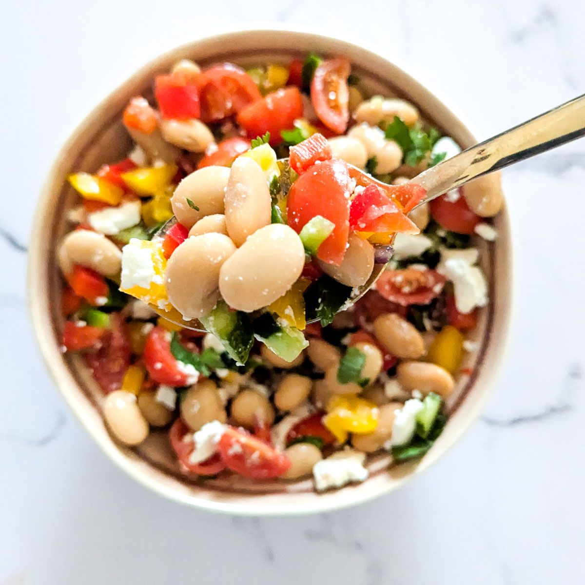 Butter bean and feta salad in a bowl, with a spooned out portion.