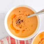 A bowl of lentil soup garnished with red pepper chili flakes.
