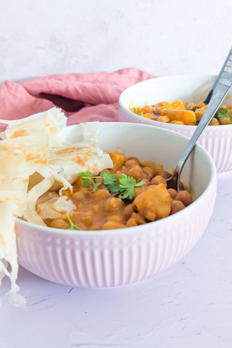 An image of chickpea and potato curry in bowls, shot from the front.