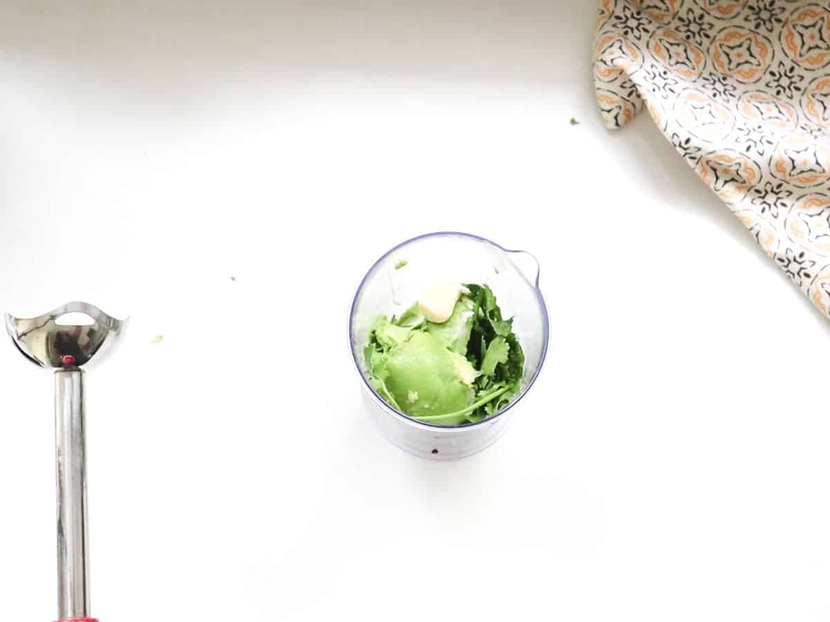 A picture of a bowl of avocado dressing next to a plate of salad.