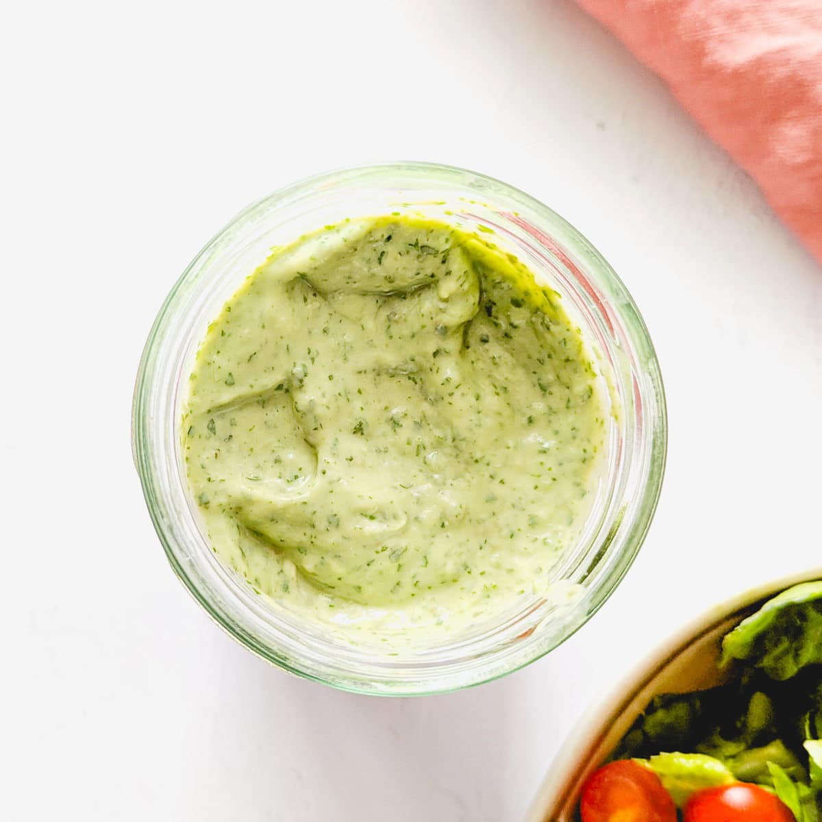 A top-down picture of avocado lime dressing next to a salad bowl.