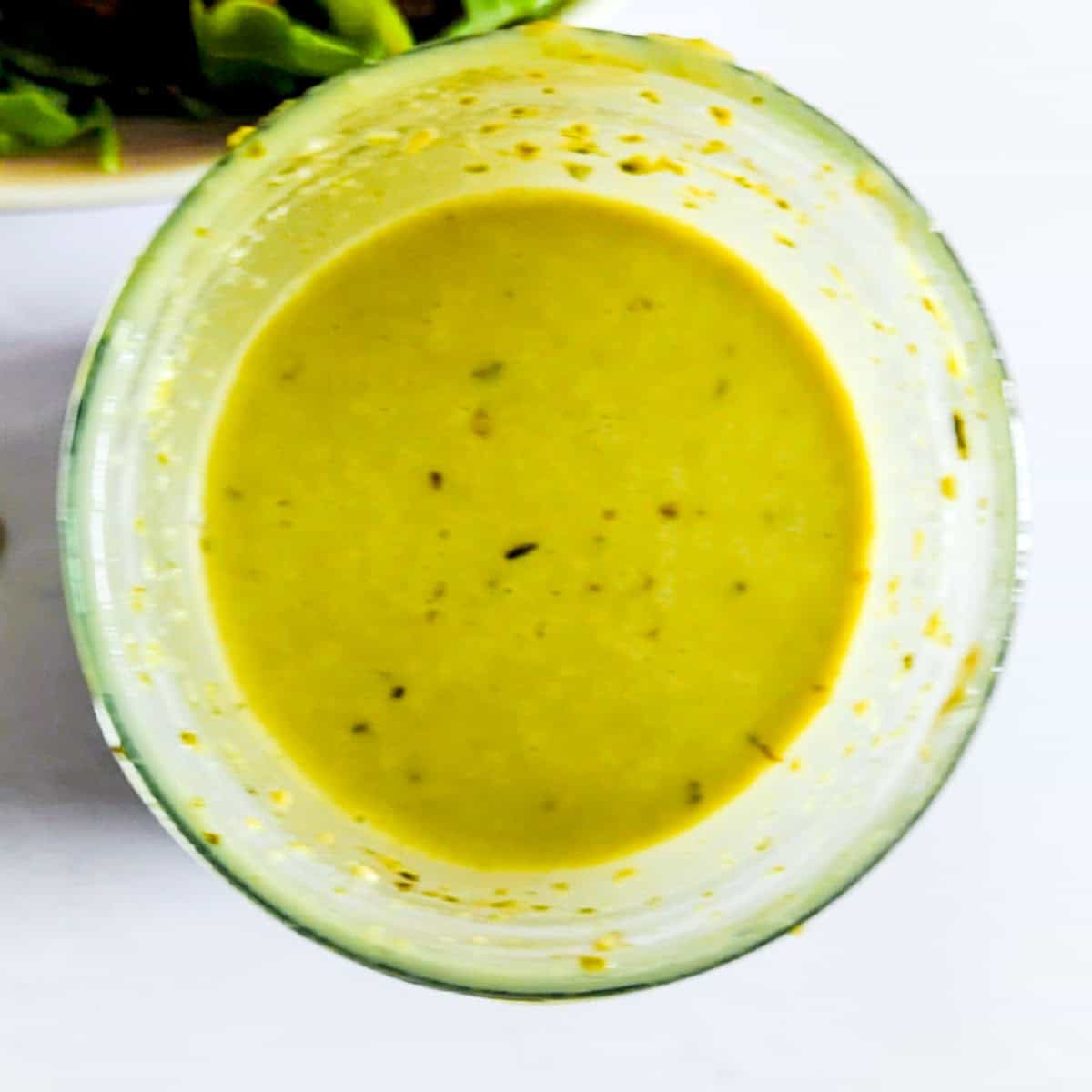 A zoomed in bird's eye picture of pesto balsamic salad dressing.