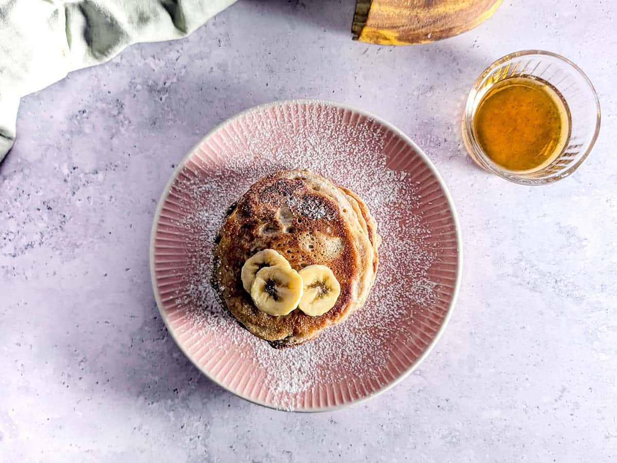 Buckwheat pancakes on a plate with some maple syrup.