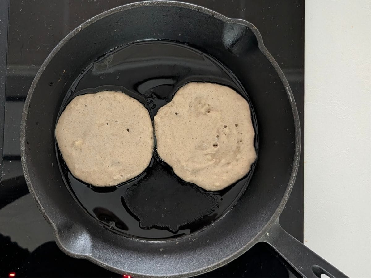 Pancakes cooking in a skillet.