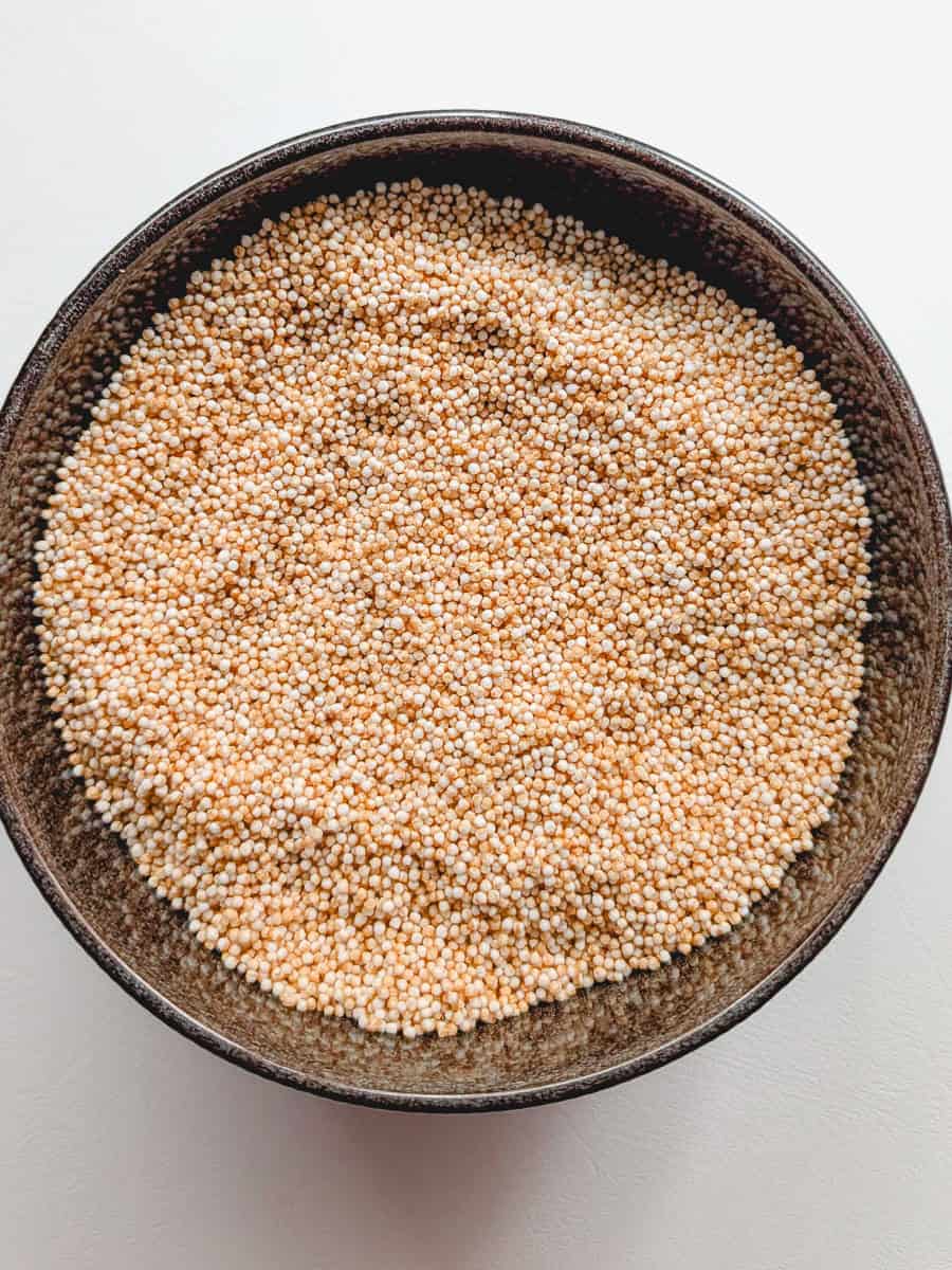 A close-up picture of amaranth seeds in a brown bowl.