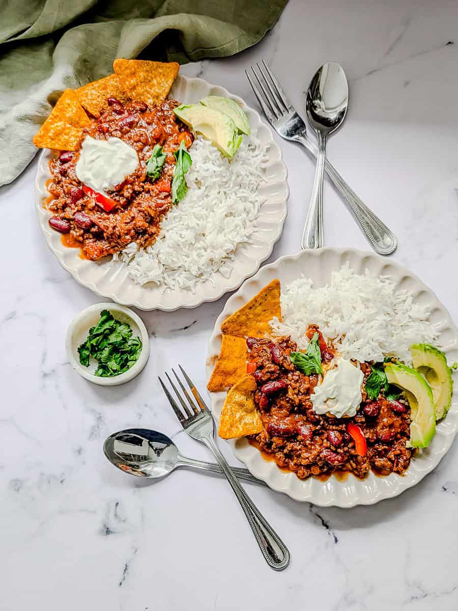 Two plates of chili con carne served with rice.