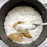 Stovetop basmati rice in a black pot with bay leaves.