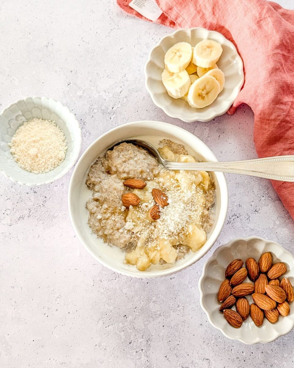 Bird’s-eye view of quinoa amaranth porridge with banana, almonds, and coconut flakes.