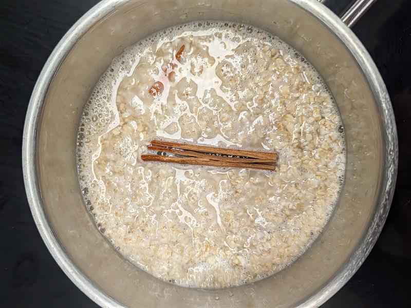 Oat porridge simmering with a cinnamon stick