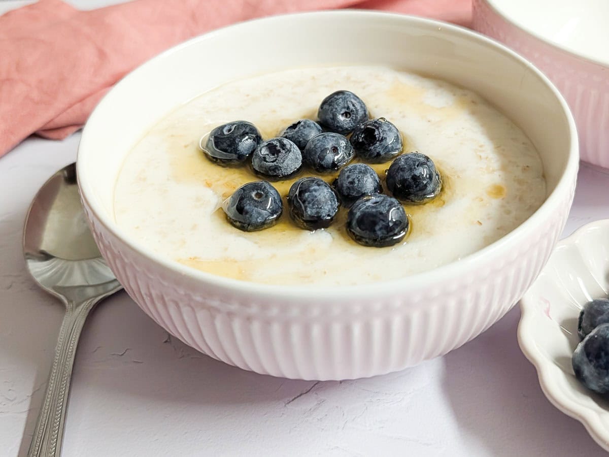 A bowl of oat porridge topped with fresh blueberries and a drizzle of honey.