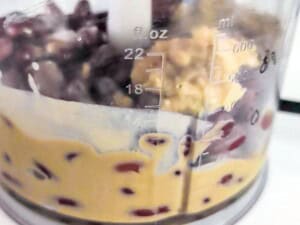 Kidney beans, tahini, garlic, lemon juice, and seasonings inside a hand blender.