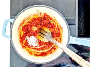 Tomatoes cooking in a pot along with some salt.