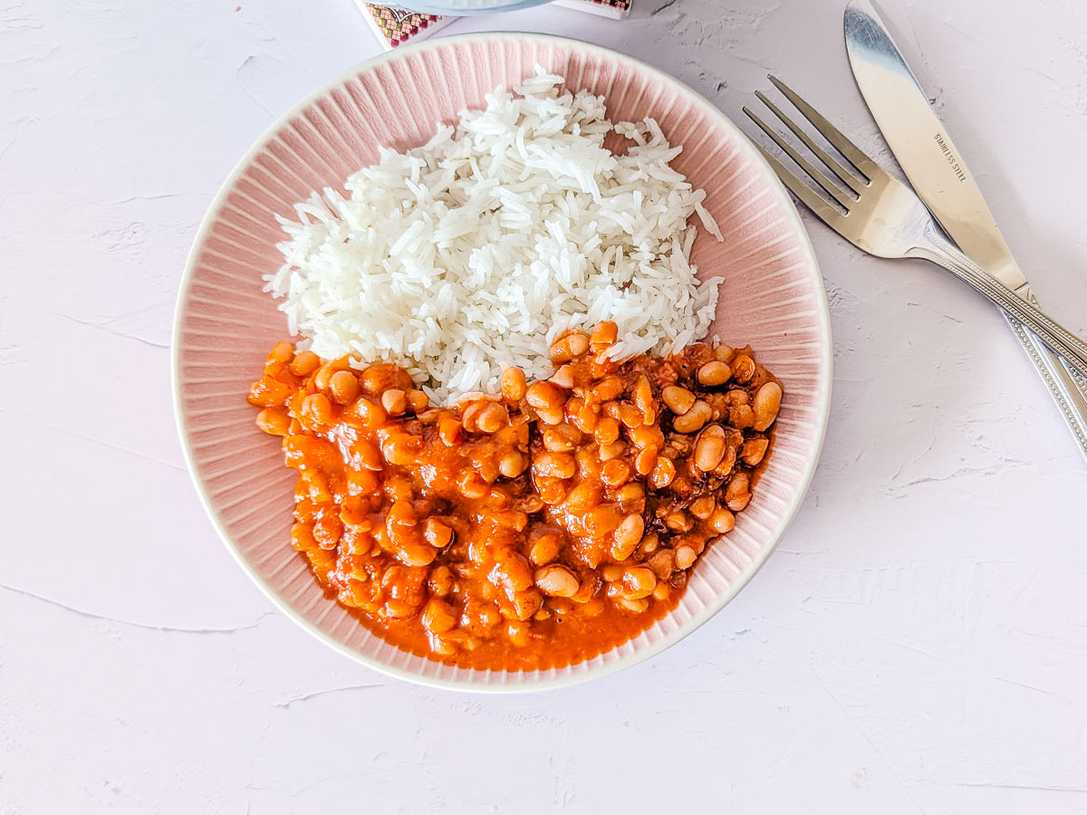 Top-down view of beans in sauce with rice on a plate