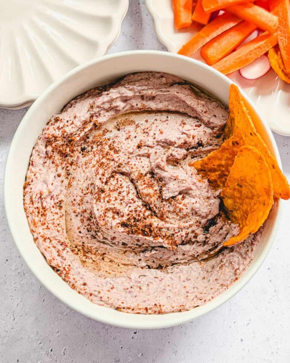 Tortilla chips dipping into a bowl of homemade red kidney bean hummus.