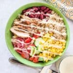 Mediterranean chicken grain bowl with quinoa, kidney beans, sweet corn, cucumber, tomatoes, and yogurt dressing.